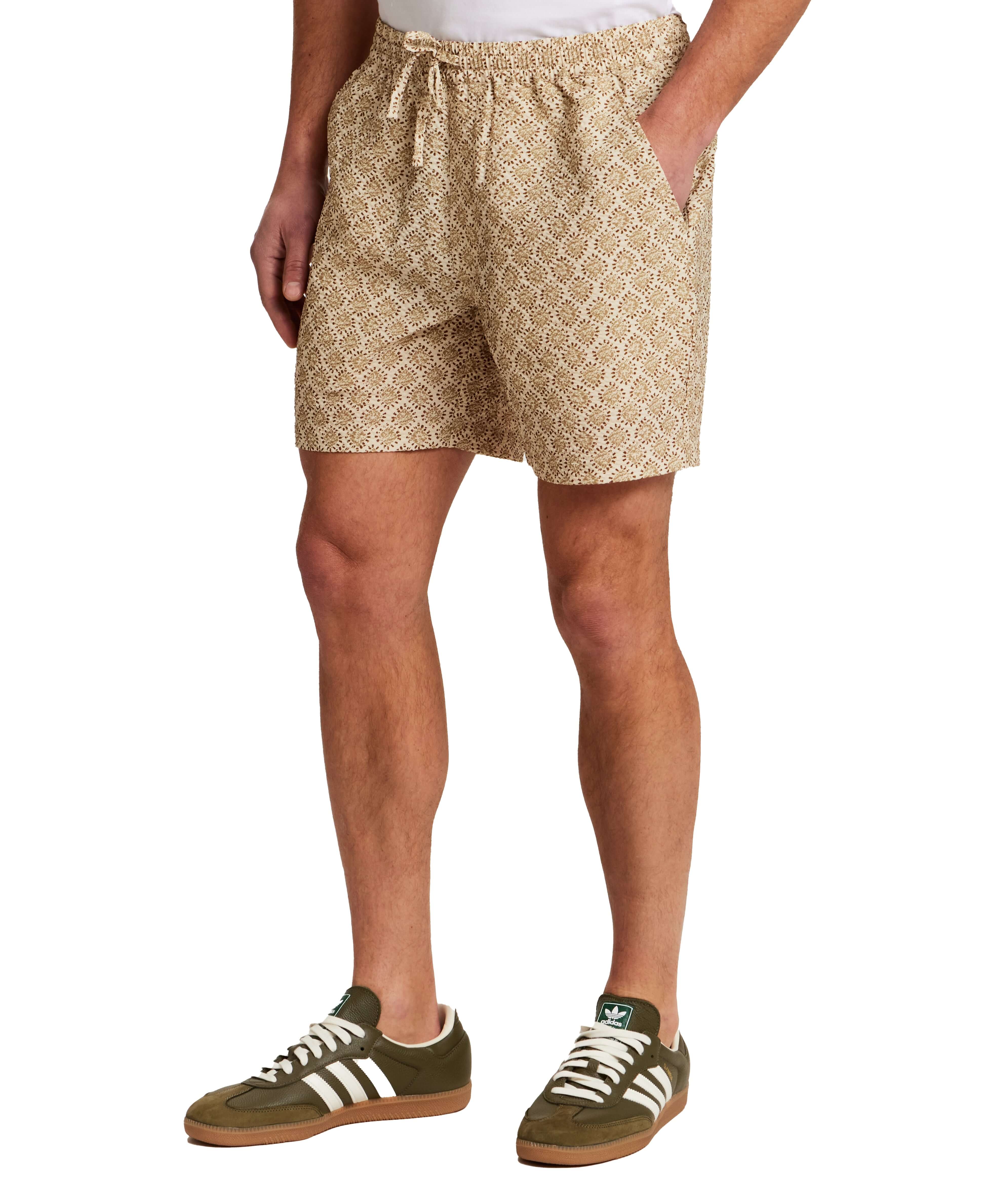 The Medallion Print Seersucker Short in Khaki modeled by a man wearing casual sneakers and an elastic waistband.