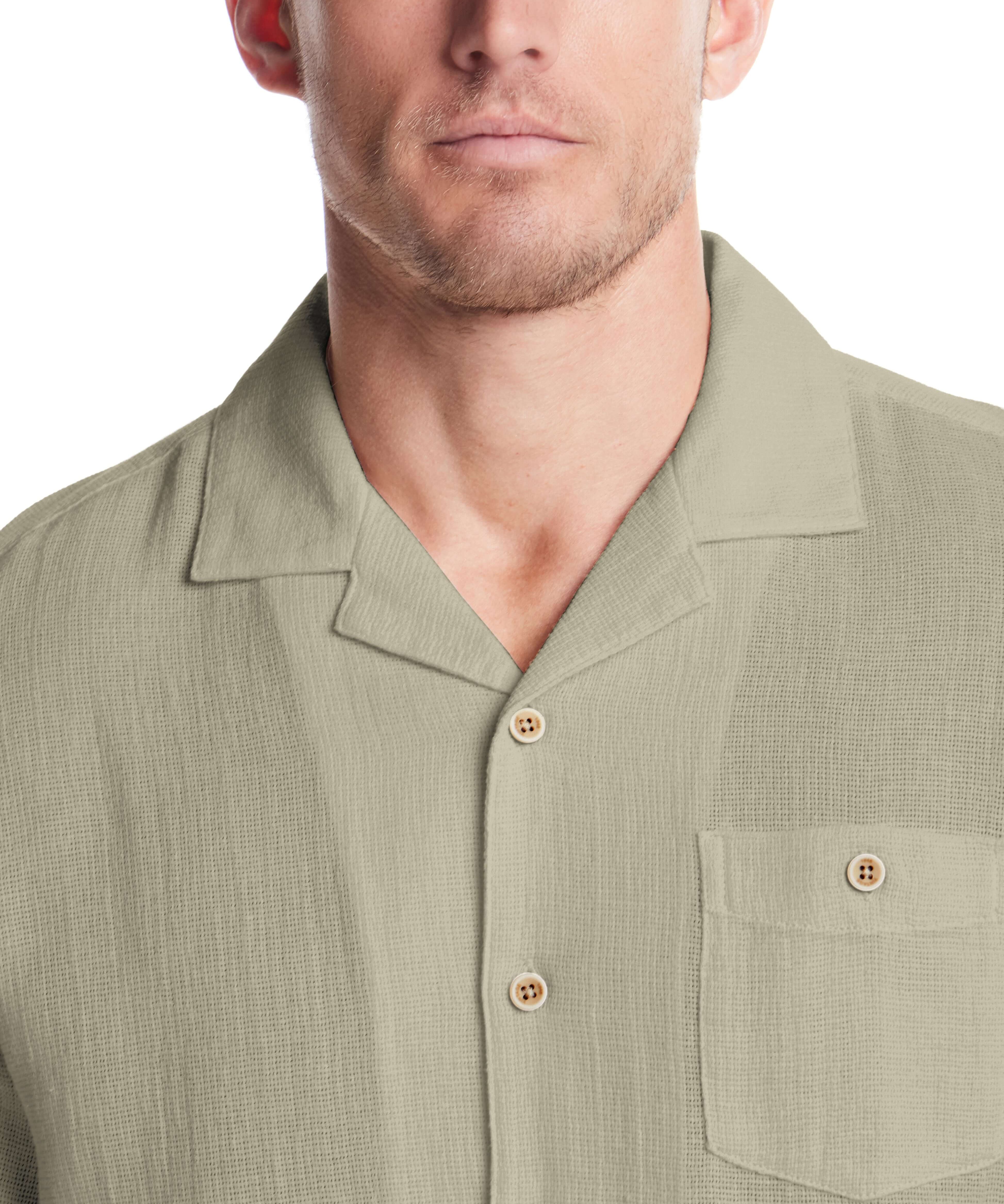Close-up of a man wearing a Short Sleeve Cotton Linen Airtex Shirt in Sea Grass with a camp collar and button-down pocket.