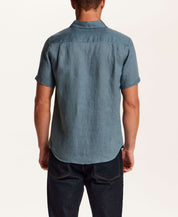 Back view of a man wearing a Short-Sleeve Linen Shirt in Blue, showcasing its relaxed fit and spread collar.