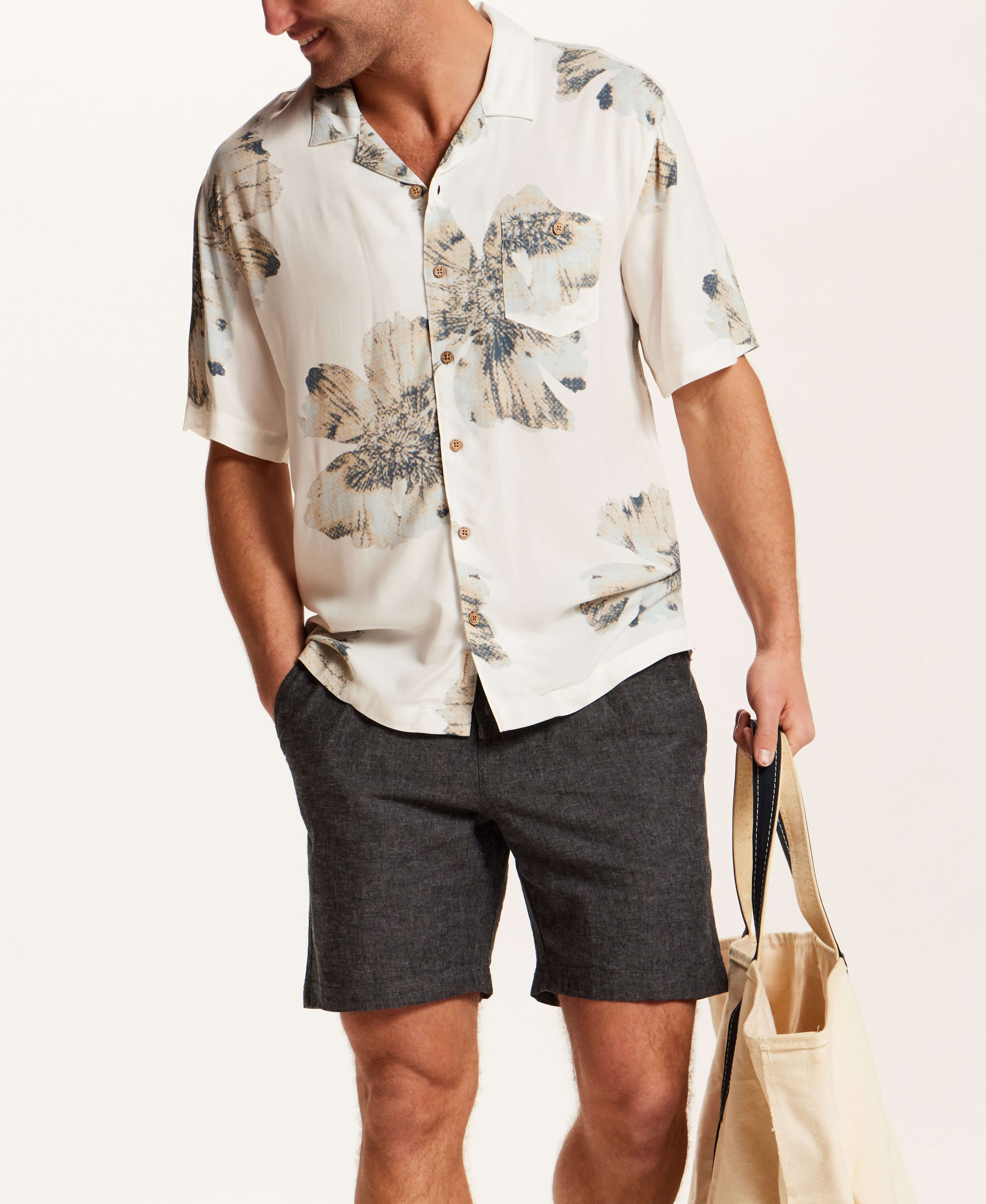 Model wearing Short Sleeve Rayon Printed Camp Shirt in Putty paired with stylish shorts and carrying a tote bag.