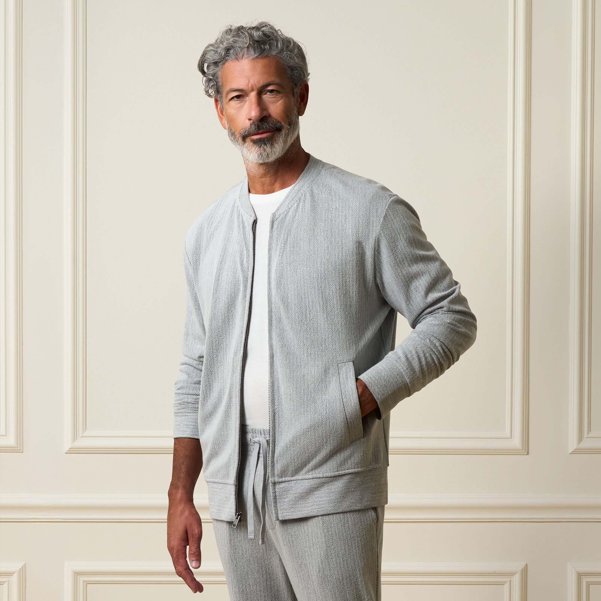 Mini Herringbone Bomber Jacket in Natural modeled by a man with grey hair, wearing a relaxed fit zip-up style.