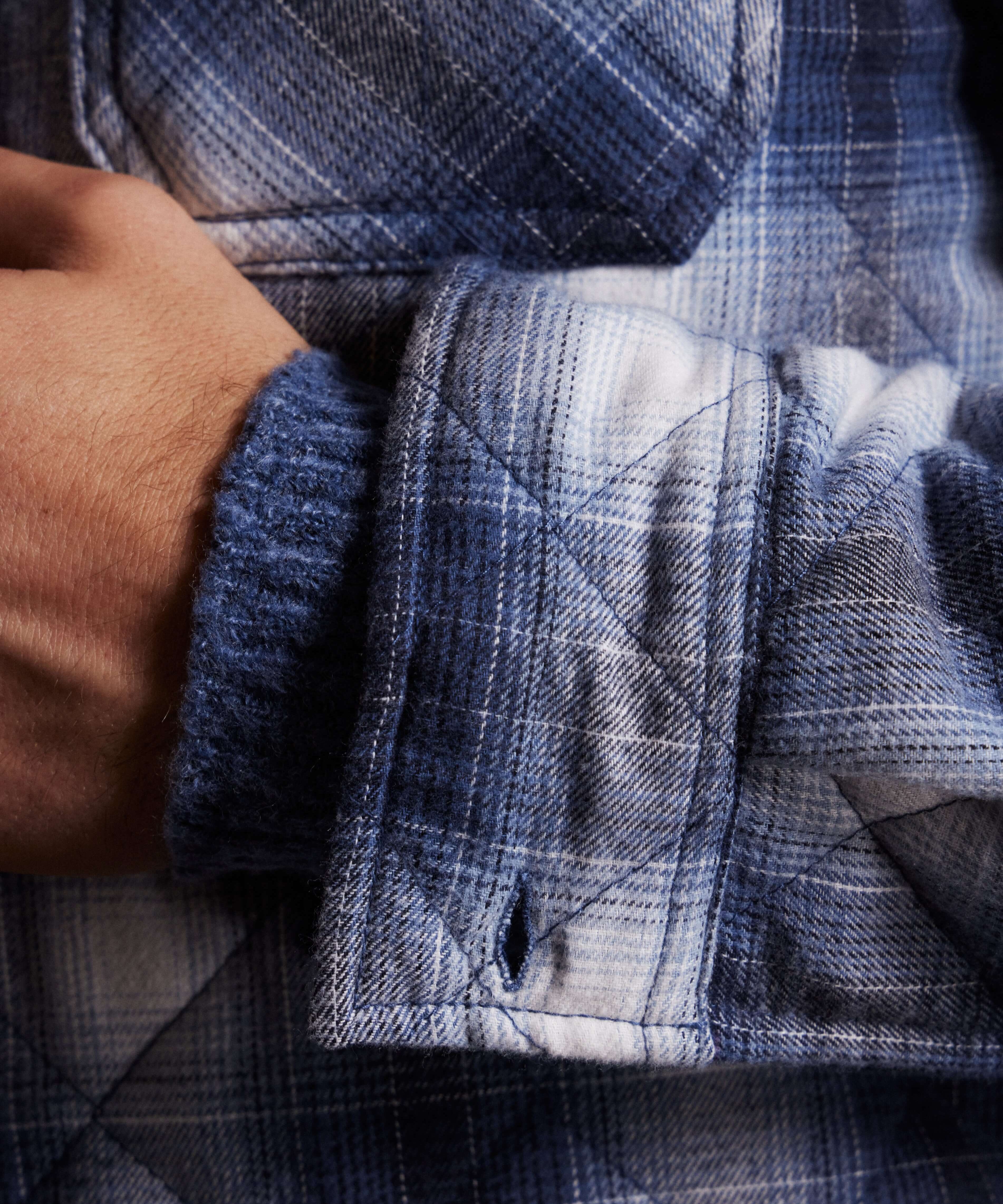 Close-up of quilted plaid shirt jacket in Quiet Harbor showcasing textured fabric and warm sleeves, ideal for winter style.