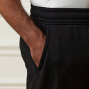 Close-up of the drawstring waistband and side pocket of the Ribbed Drawstring Pant in Black.