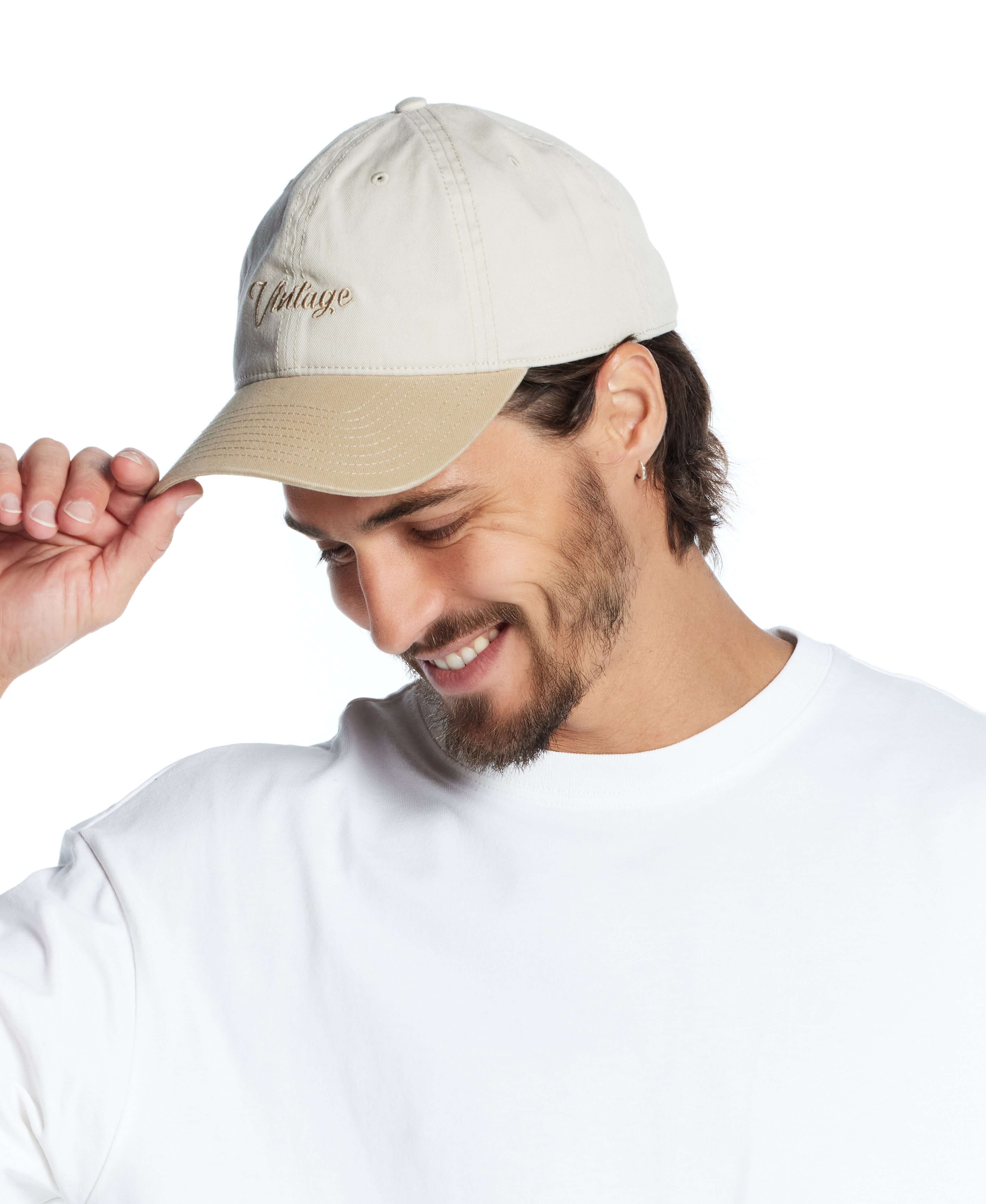 Man smiling and wearing a khaki adjustable Script Vintage Hat, perfect for casual outfits.
