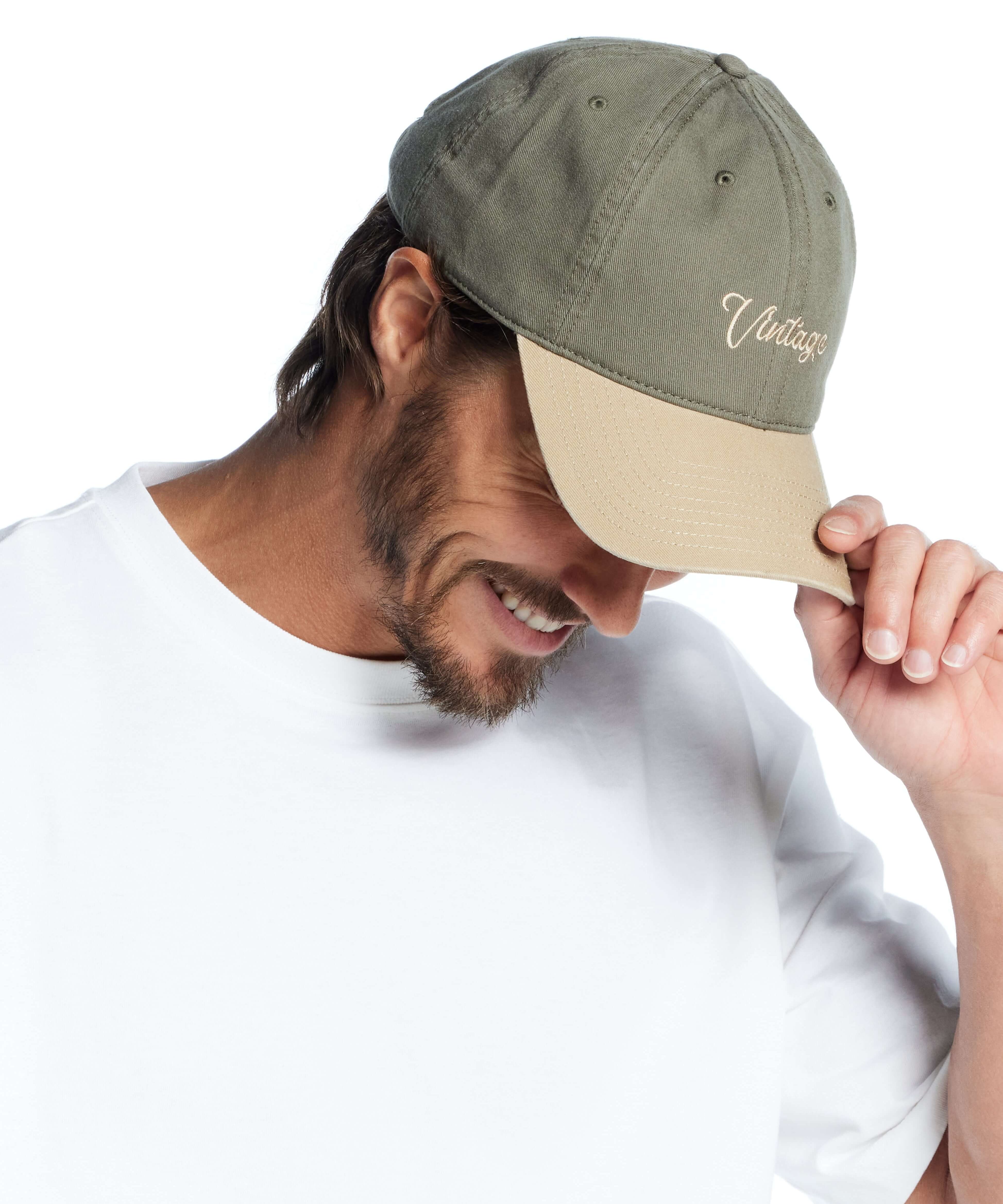 Man wearing an adjustable Script Vintage Hat in Olive, showcasing a stylish and casual look.