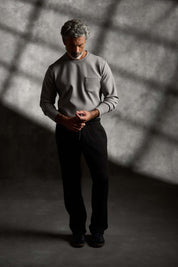 Scuba Crew Neck in Grey worn by a model standing in a shadowy setting, showcasing its modern design and relaxed fit.