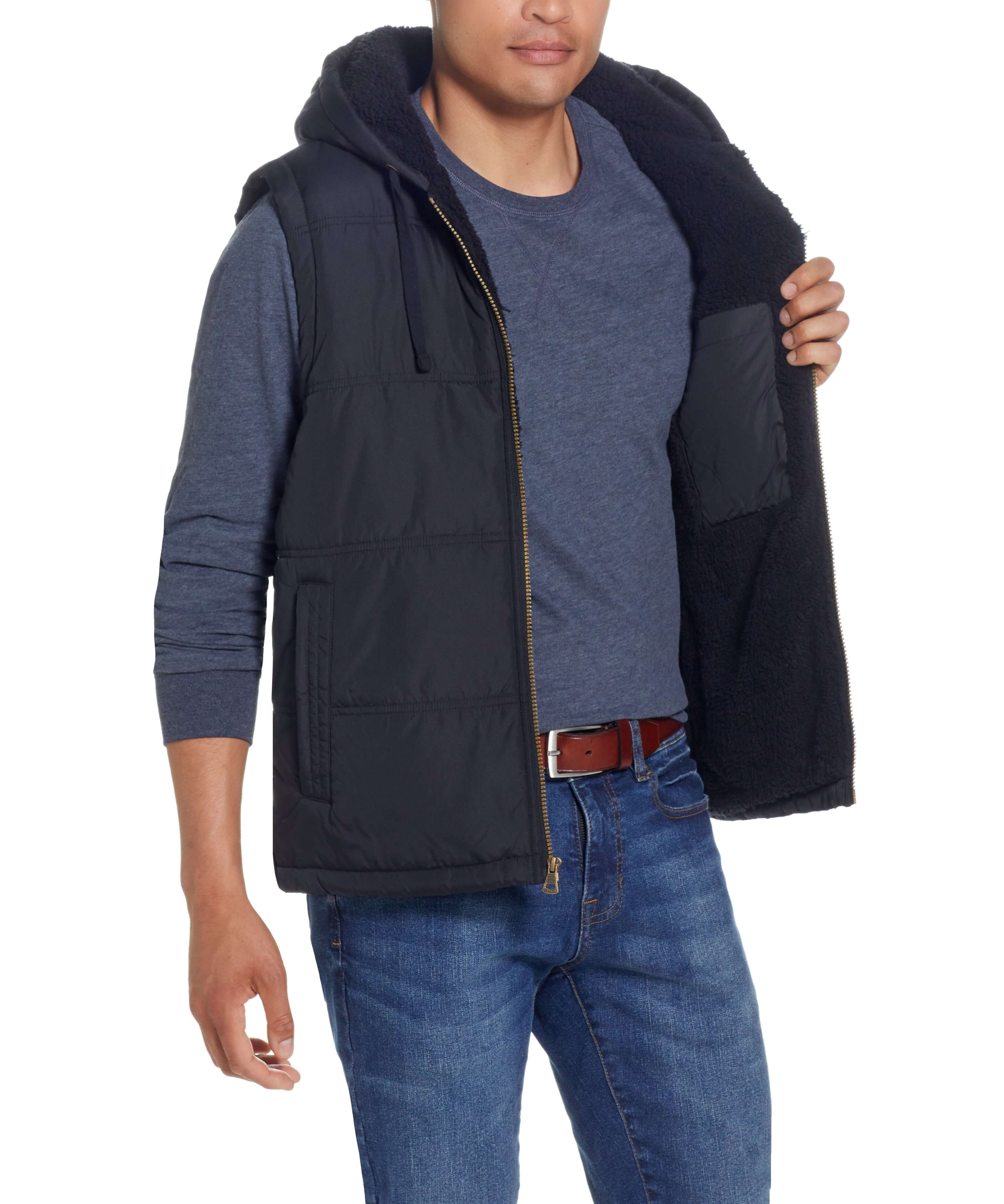 Sherpa lined hooded puffer vest in black on male model, showcasing cozy design and side slash pockets.