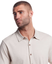 Model wearing a short sleeve button front coat in natural with a textured jacquard pattern and collar.