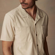 Short sleeve corduroy cabana shirt in cream on model, featuring button front and chest pockets.