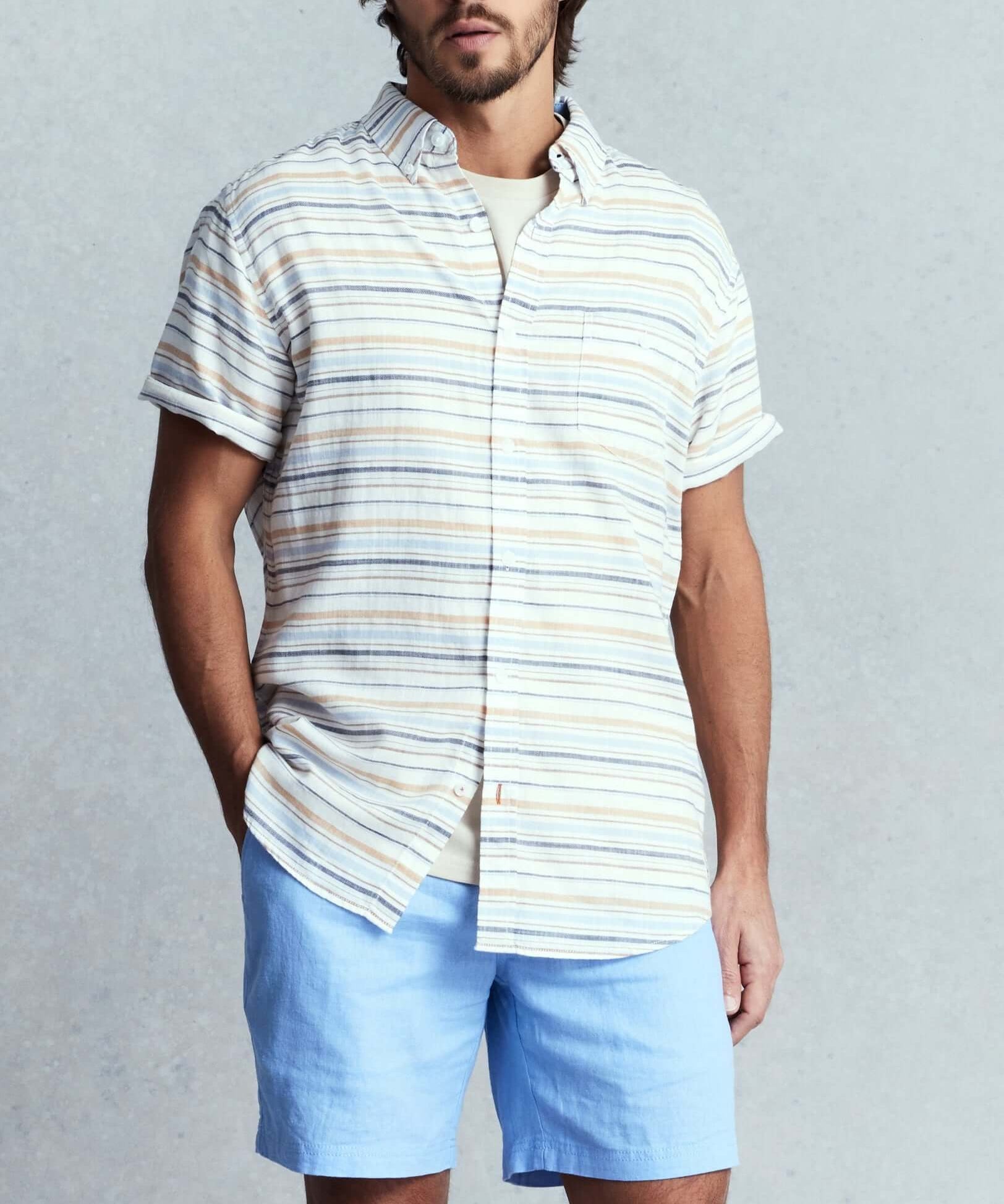 Men's short sleeve country twill striped shirt in white sand, featuring cuffed sleeves and a chest pocket, styled with blue shorts.