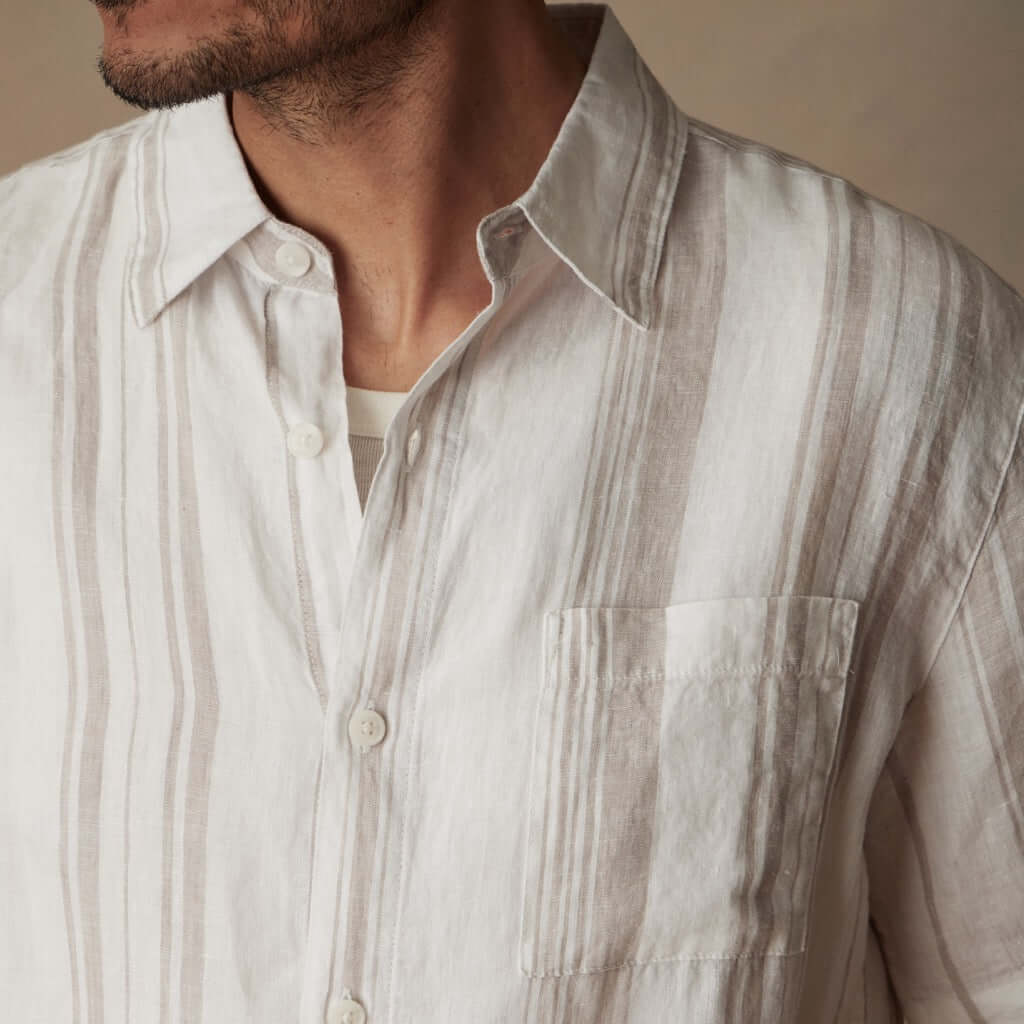 Close-up of a man wearing a short sleeve faux linen cotton shirt in natural stripe with a button down collar.