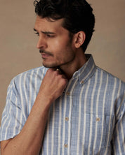 Model wearing short sleeve faux linen cotton shirt in vista blue, featuring button down collar and chest pocket.