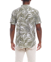 Back view of a man in a short sleeve floral shirt in lichen green, featuring a leafy print, paired with light-colored pants.