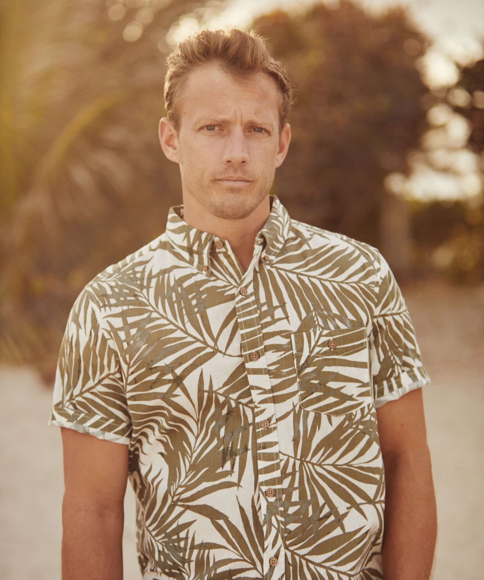 Model wearing a short sleeve floral shirt in lichen green, perfect for casual summer outings.