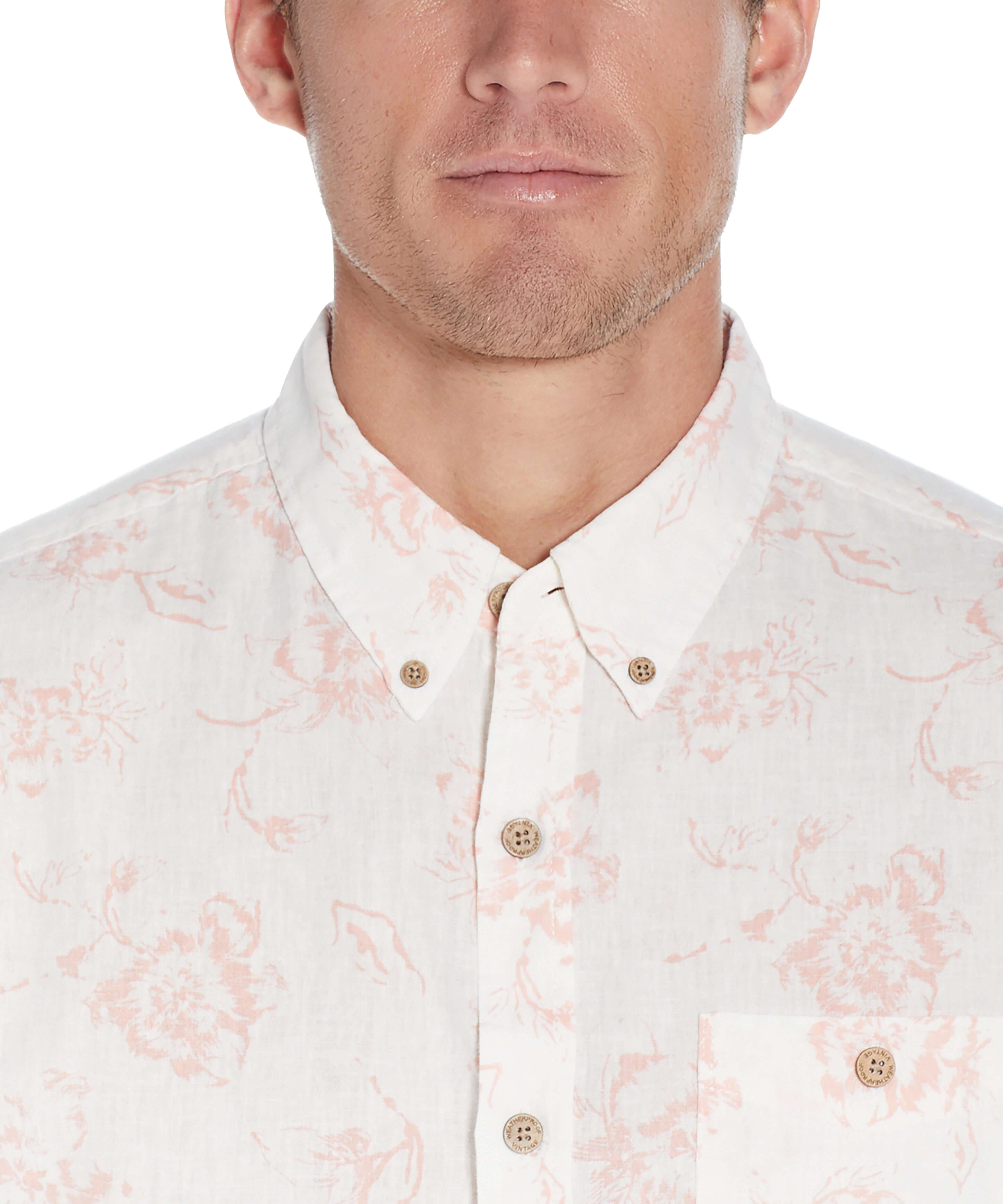 Close-up of a man wearing a short sleeve pink floral button-down shirt, showcasing its relaxed fit and linen cotton fabric.