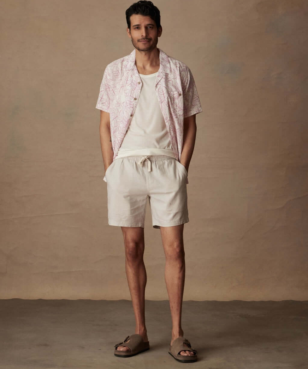 Man wearing a Short Sleeve Linen Cotton Camp Shirt in Wild Rose, paired with beige shorts and sandals.
