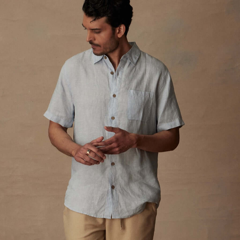 Man modeling a classic short sleeve linen shirt in celestial blue with a button closure and chest pocket.
