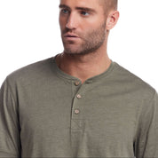 Close-up of a man wearing a short sleeve melange henley shirt in olive, featuring a three-button placket and rib-knit neck.