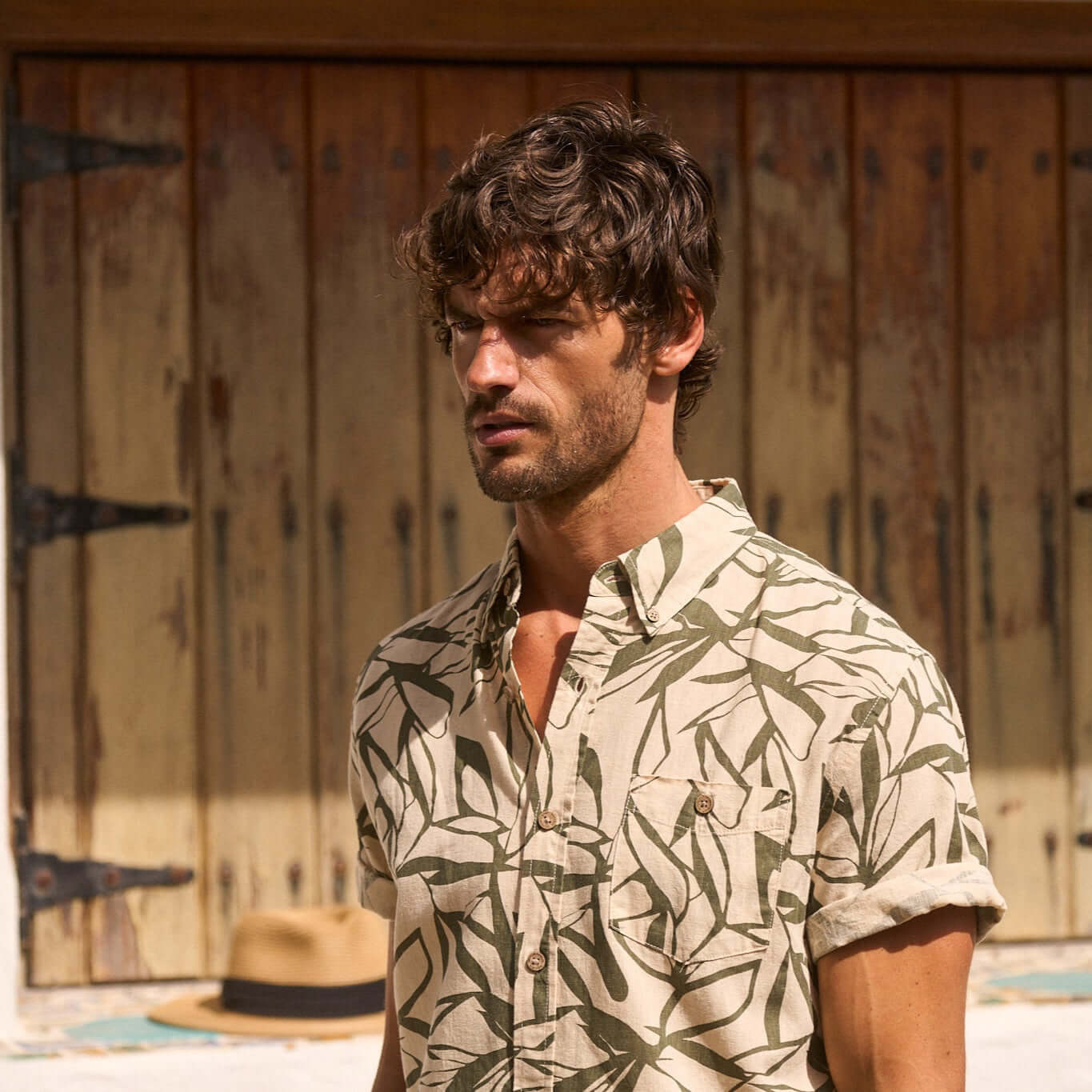 Man wearing a short sleeve print linen cotton shirt in Four Leaf Clover design, featuring an abstract leaf pattern.