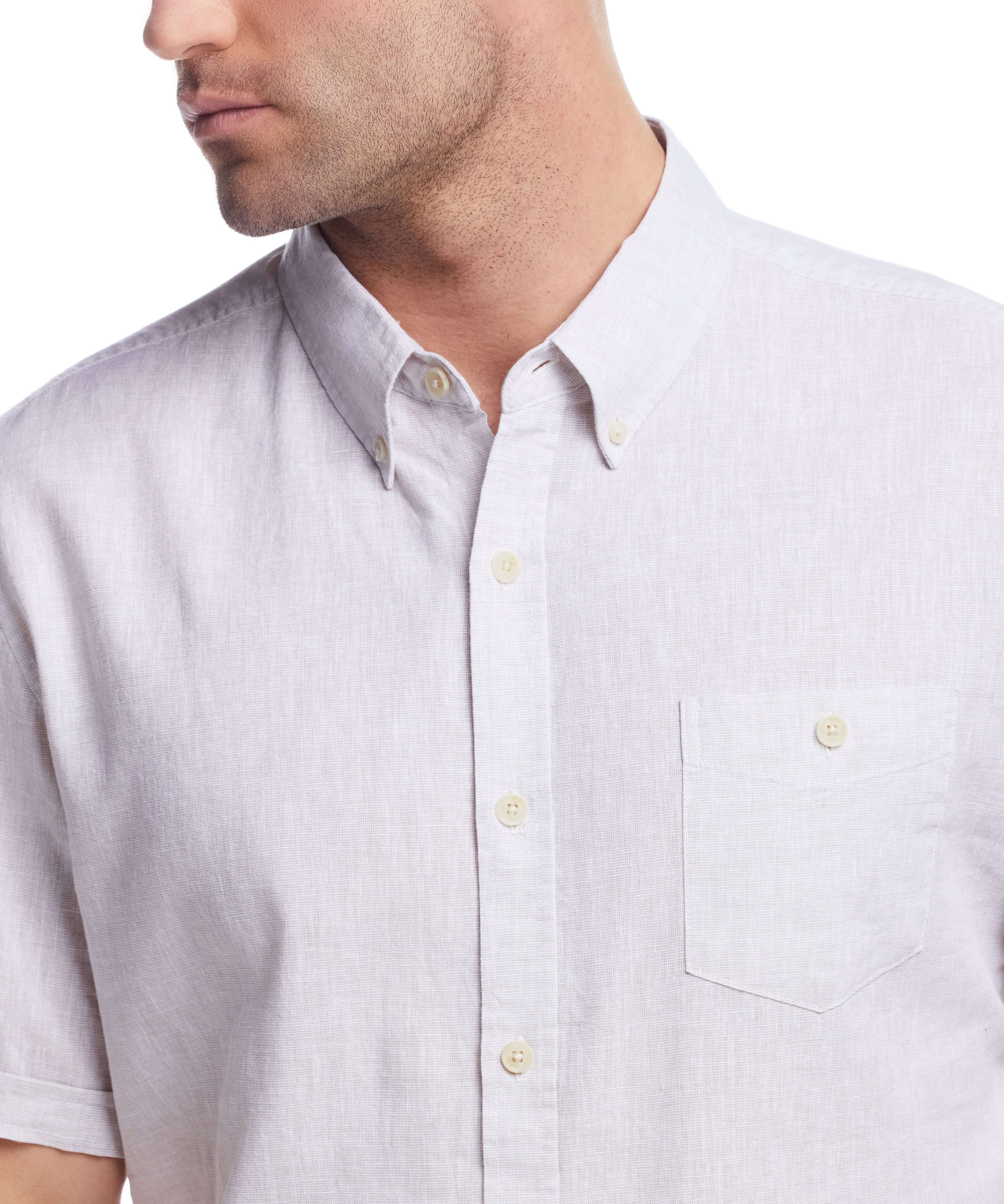 Close-up of a man wearing a short sleeve solid linen cotton shirt in natural color, featuring a button-down collar.