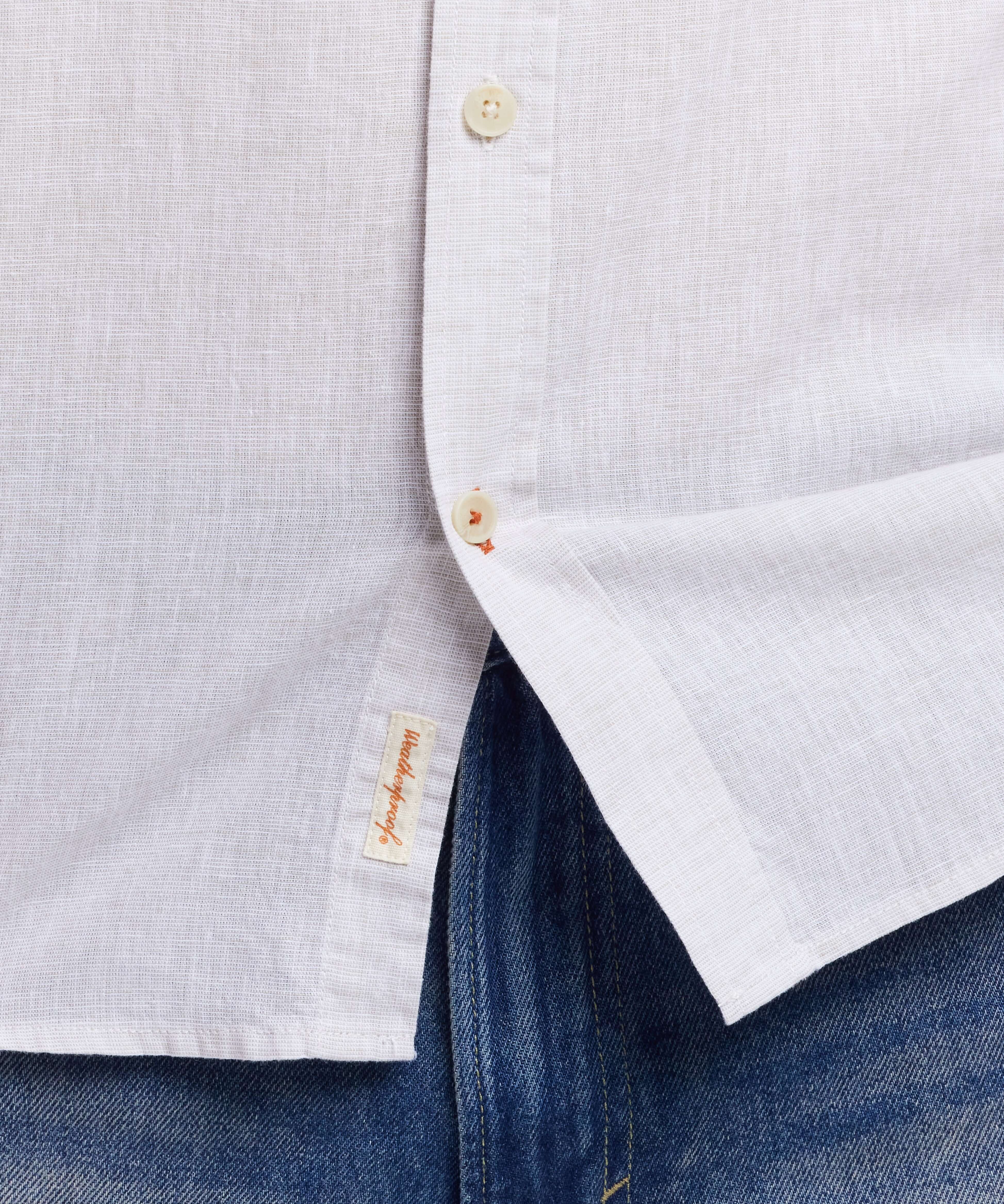 Close-up of a short sleeve solid linen cotton shirt in natural color with button details and a casual fit.