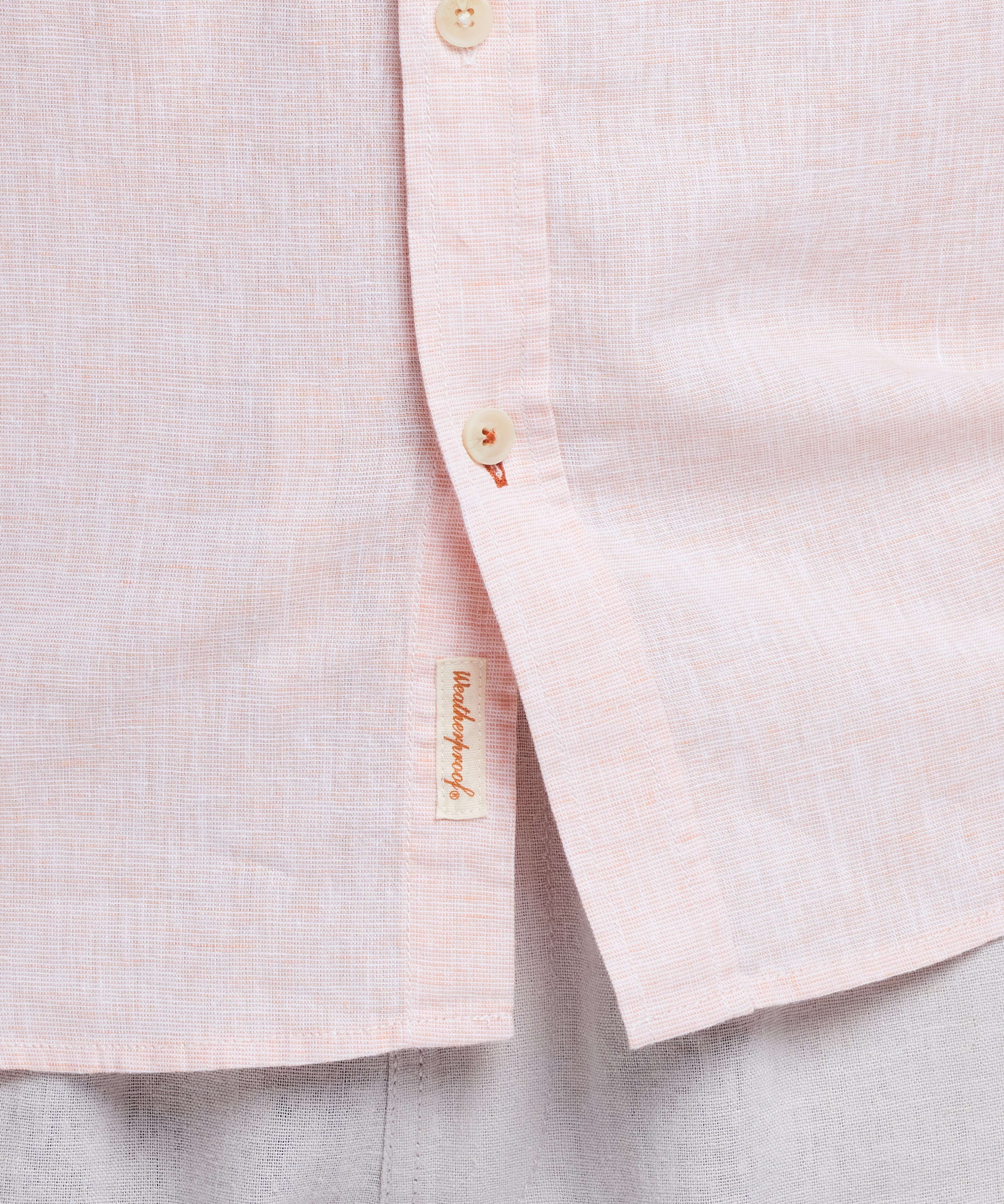 Close-up of a light pink linen shirt with buttons, featuring a casual and stylish blend of comfort and elegance.