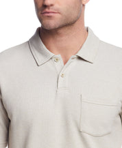 Close-up of a man in a short sleeve twill polo in natural, featuring a polo collar and chest pocket.