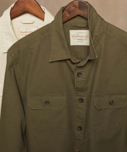 Slub canvas work shirt in dark olive, featuring a spread collar and dual chest pockets, displayed on wooden hangers.