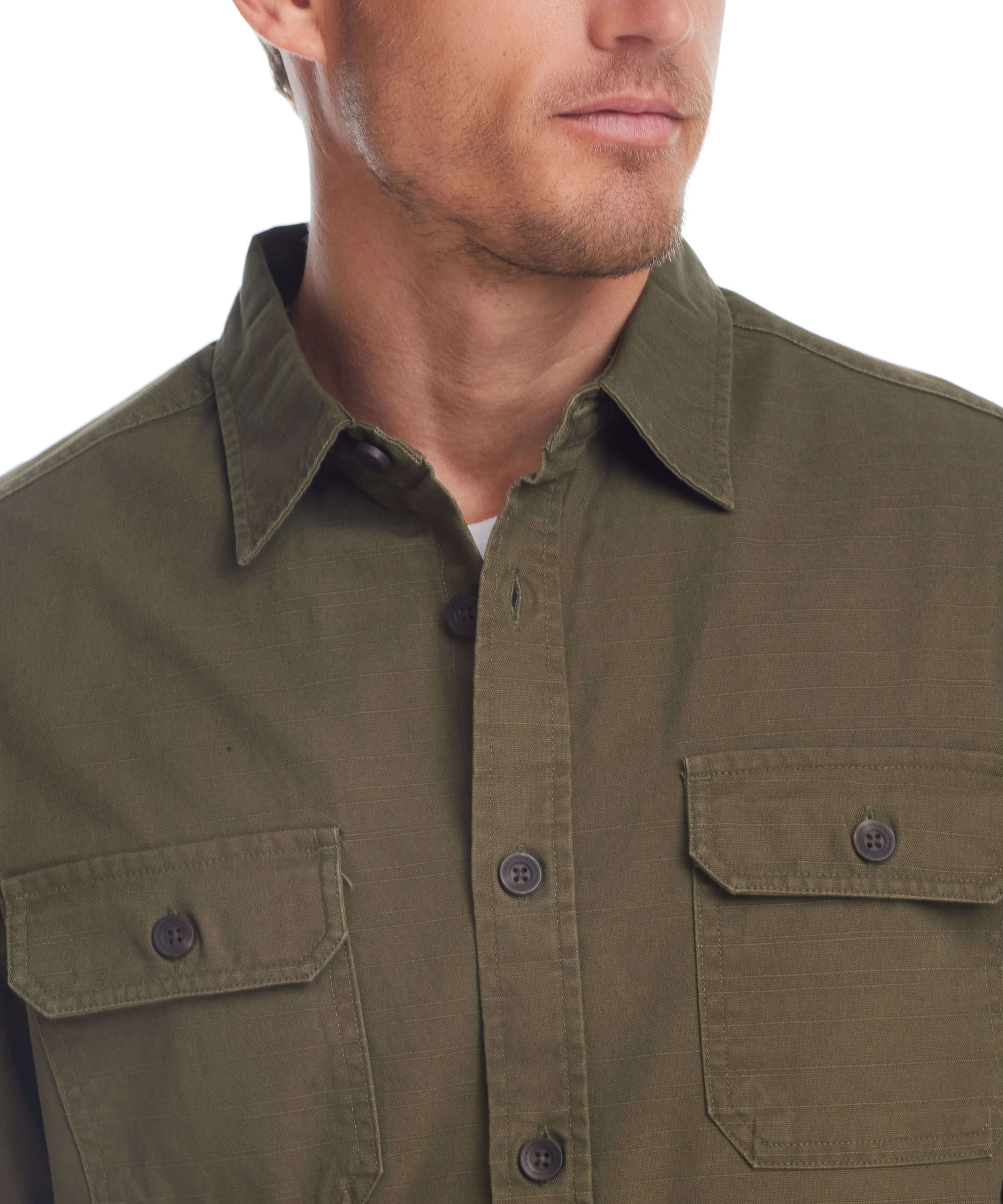 Close-up of a man wearing a dark olive slub canvas work shirt with two chest flap pockets and button-front closure.
