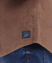 Close-up of the label on a brown thin wale solid cord shirt, showcasing vintage branding and corduroy texture.