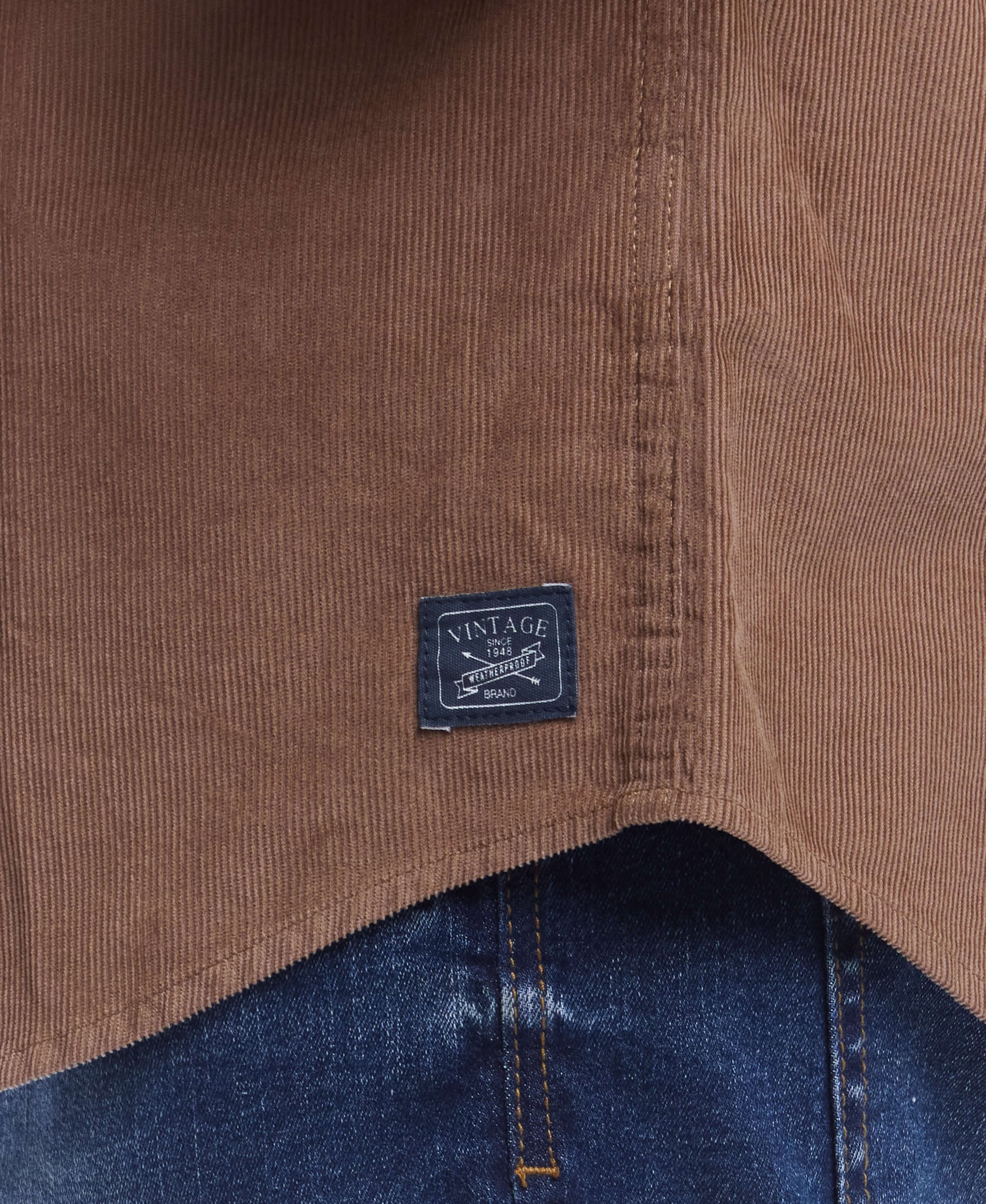 Close-up of the label on a brown thin wale solid cord shirt, showcasing vintage branding and corduroy texture.