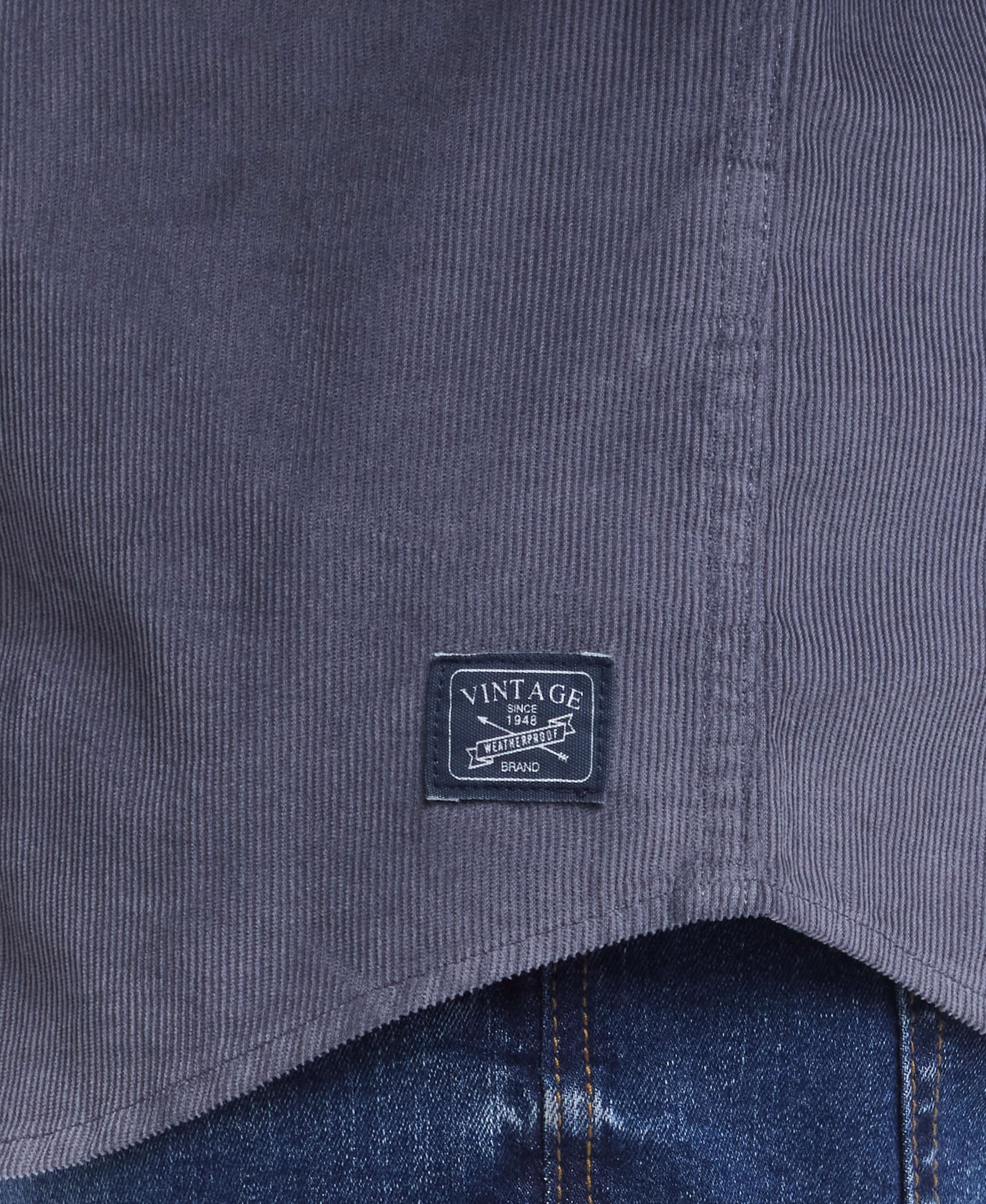Close-up of THIN WALE SOLID CORD SHIRT tag showcasing vintage logo on textured fabric in poppy seed color.