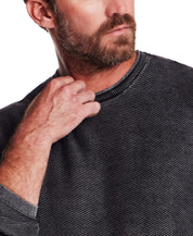 Close-up of a man wearing the Twill Stonewash Sweater in Jet Black, showcasing its ribbed neckline and textured fabric.