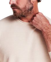 Close-up of a man wearing the Twill Stonewash Sweater in Natural, showcasing its textured fabric and roll-neck design.