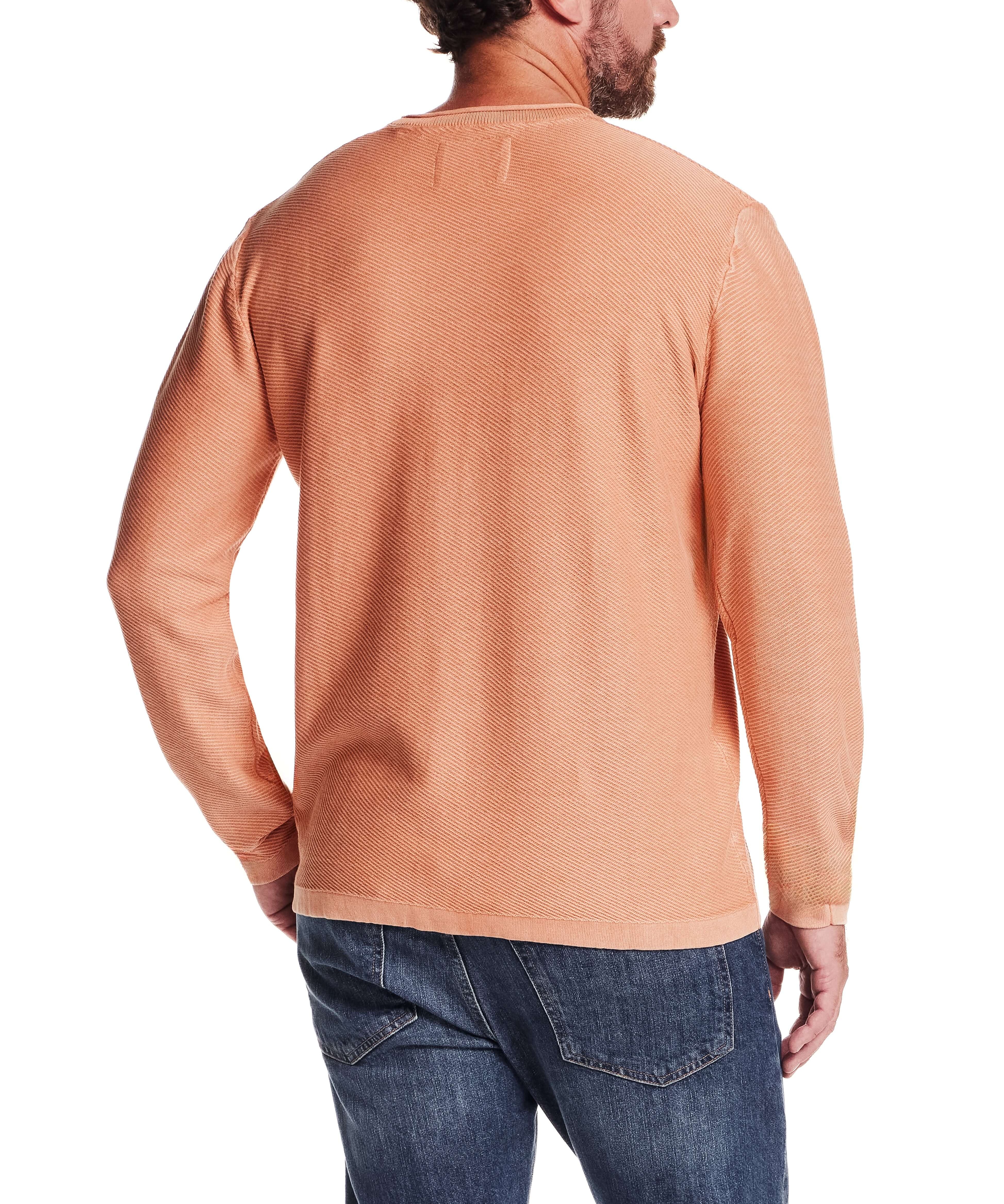Back view of a man wearing a Twill Stonewash Sweater in Shell Coral, showcasing its textured knit and roll-neck design.