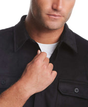 Close-up of a man wearing a black unlined sueded shirt jacket, showcasing button flap chest pockets and a stylish collar.