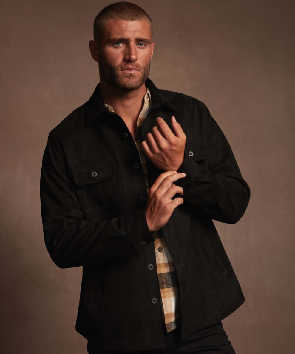 Model wearing a black unlined sueded shirt jacket with functional pockets, showcasing a soft, luxurious fabric.