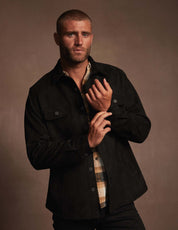 Model wearing a black unlined sueded shirt jacket with functional pockets, showcasing a soft, luxurious fabric.