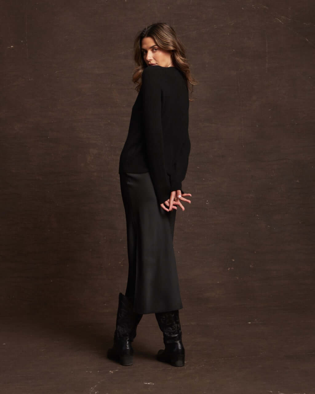 Model wearing a women's black cashmere long sleeve sweater with a sleek skirt, showcasing a classic winter style.