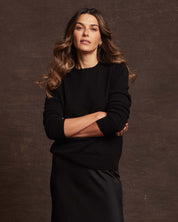Woman wearing a women's cashmere long sleeve solid crew in black, showcasing its classic fit and soft texture.