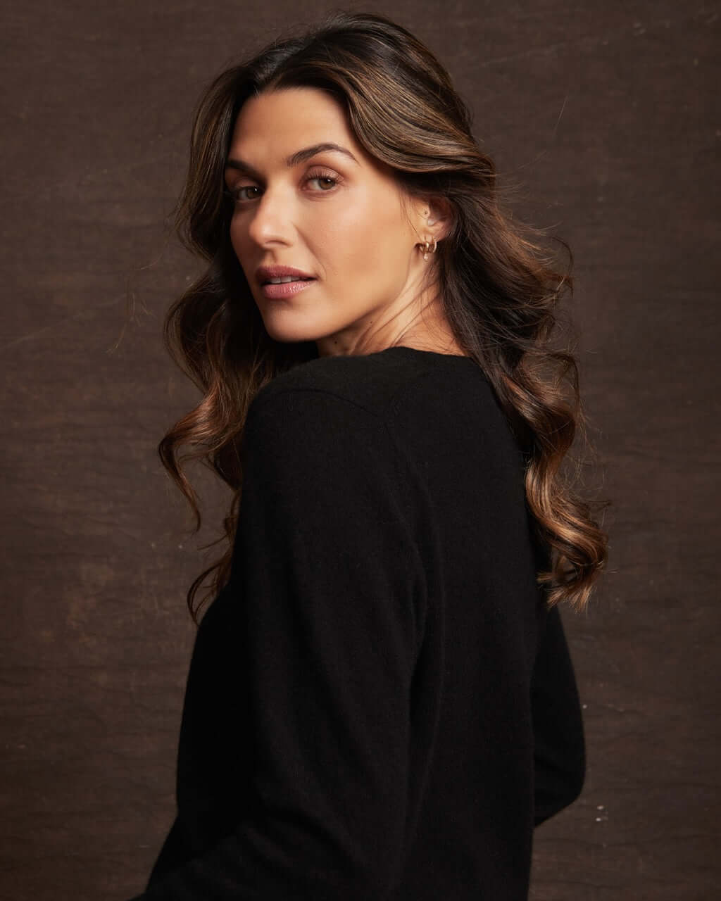 Model showcasing a women's black cashmere long sleeve sweater with V-neckline and ribbed cuffs.