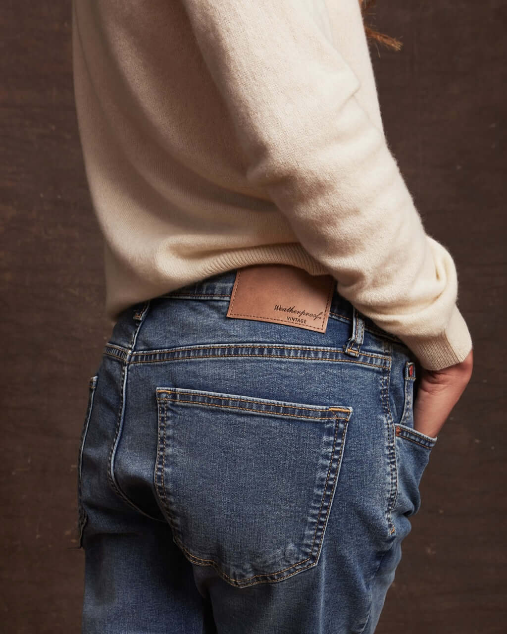 Model wearing a women's ecru cashmere sweater with blue jeans, showcasing a classic look and cozy style.
