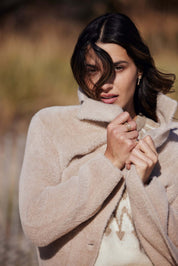 Woman wearing a plush apricot coatigan outdoors, showcasing its soft fabric and button closure.