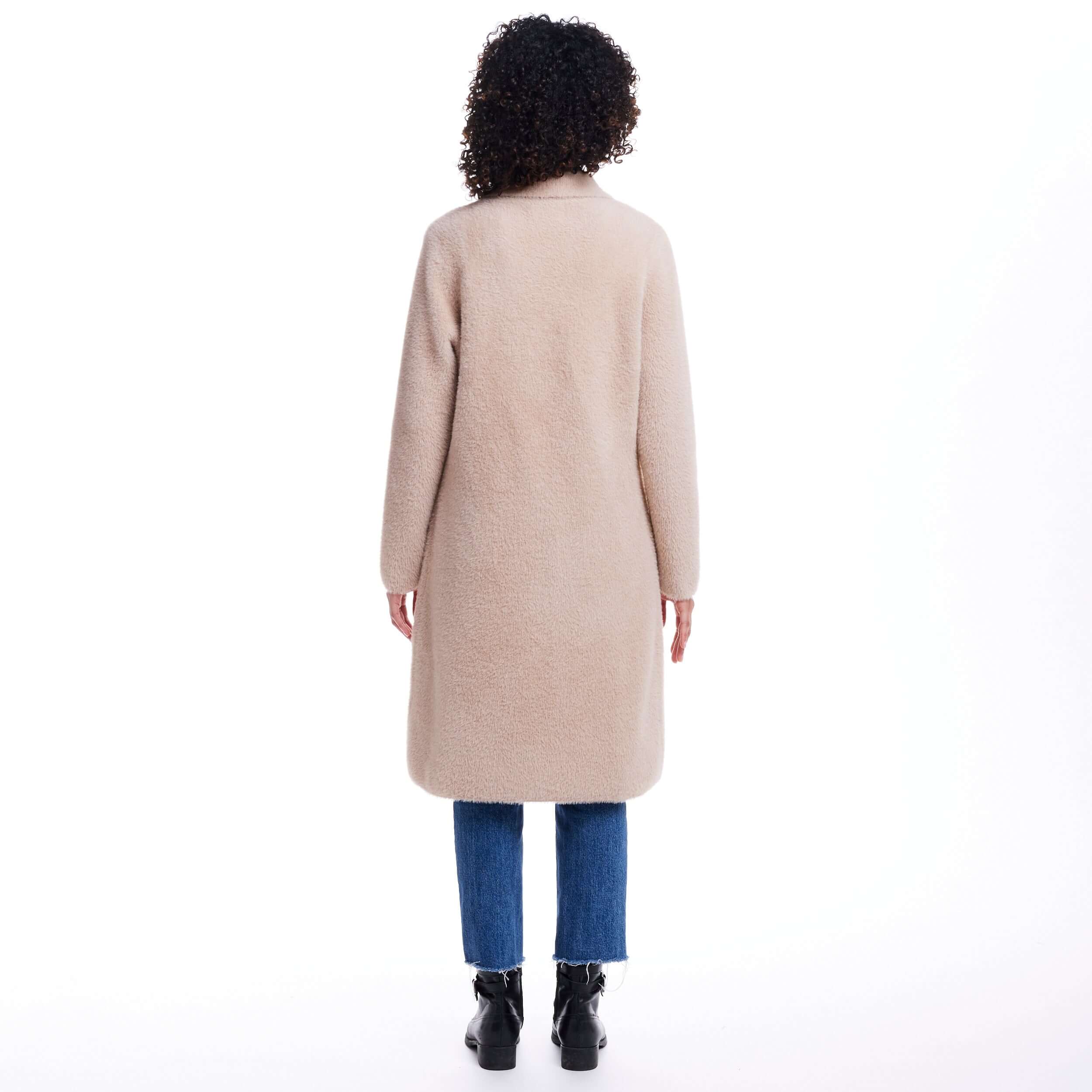 Back view of a woman wearing an apricot plush coatigan, featuring a cozy design and casual denim style.