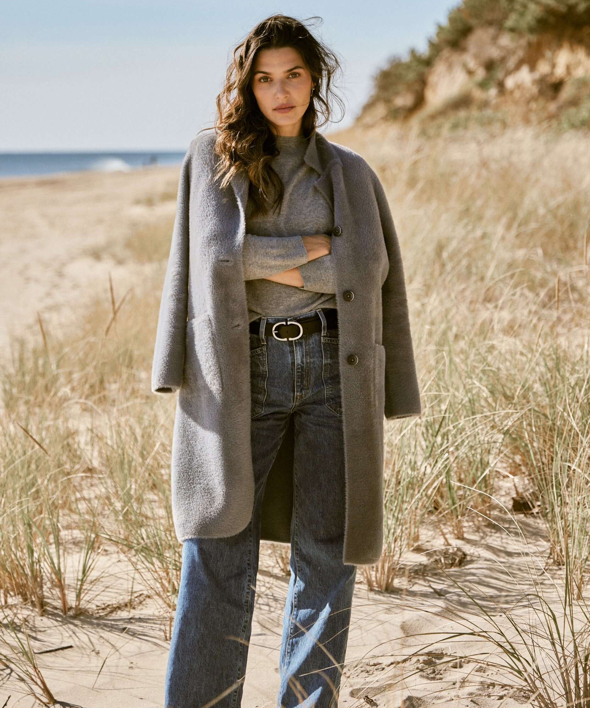 Model wearing Women's Plush Coatigan in Mid Charcoal on a beach, styled with jeans and a grey sweater.