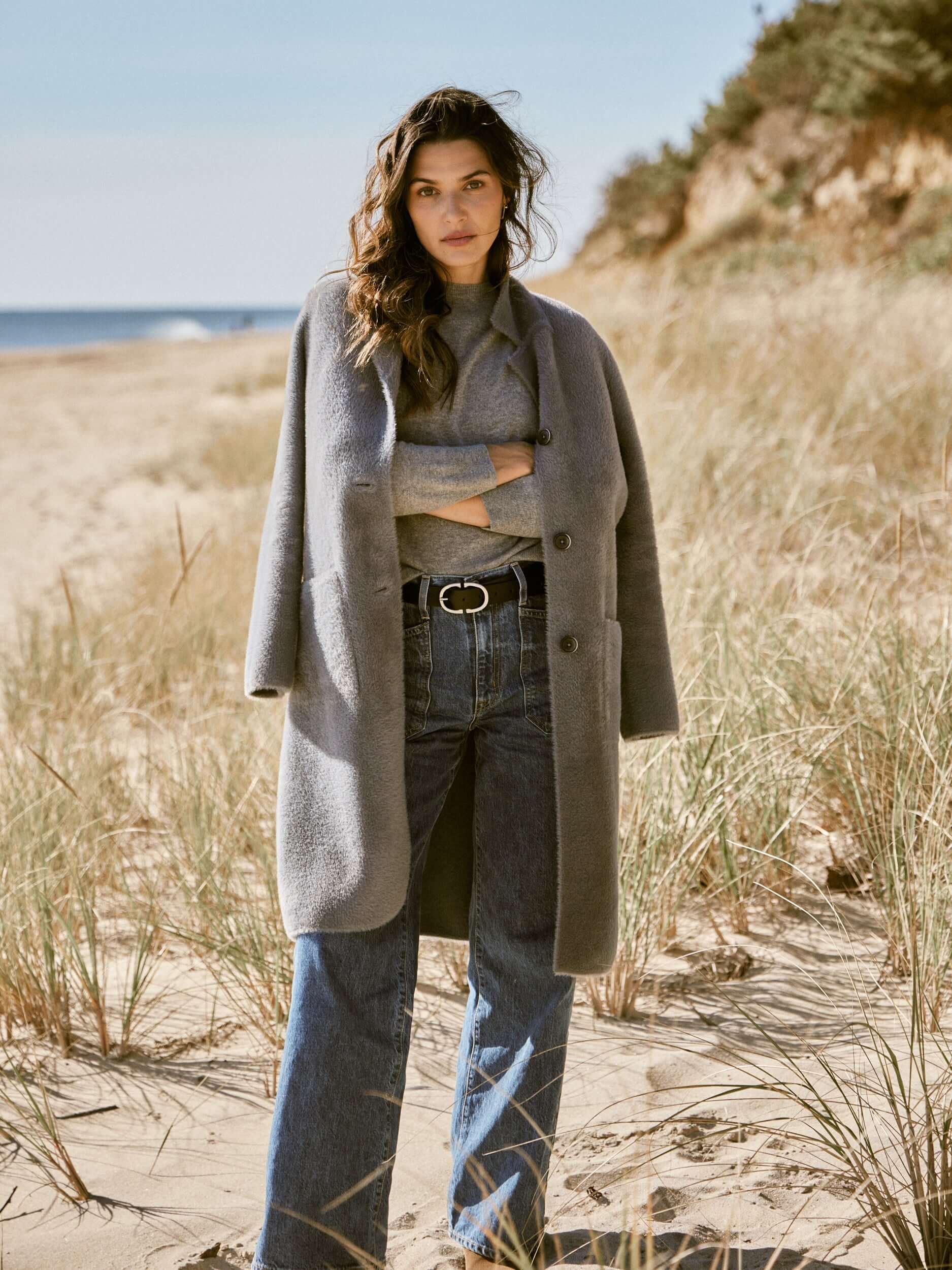 Model wearing Women's Plush Coatigan in Mid Charcoal on a beach, styled with jeans and a grey sweater.