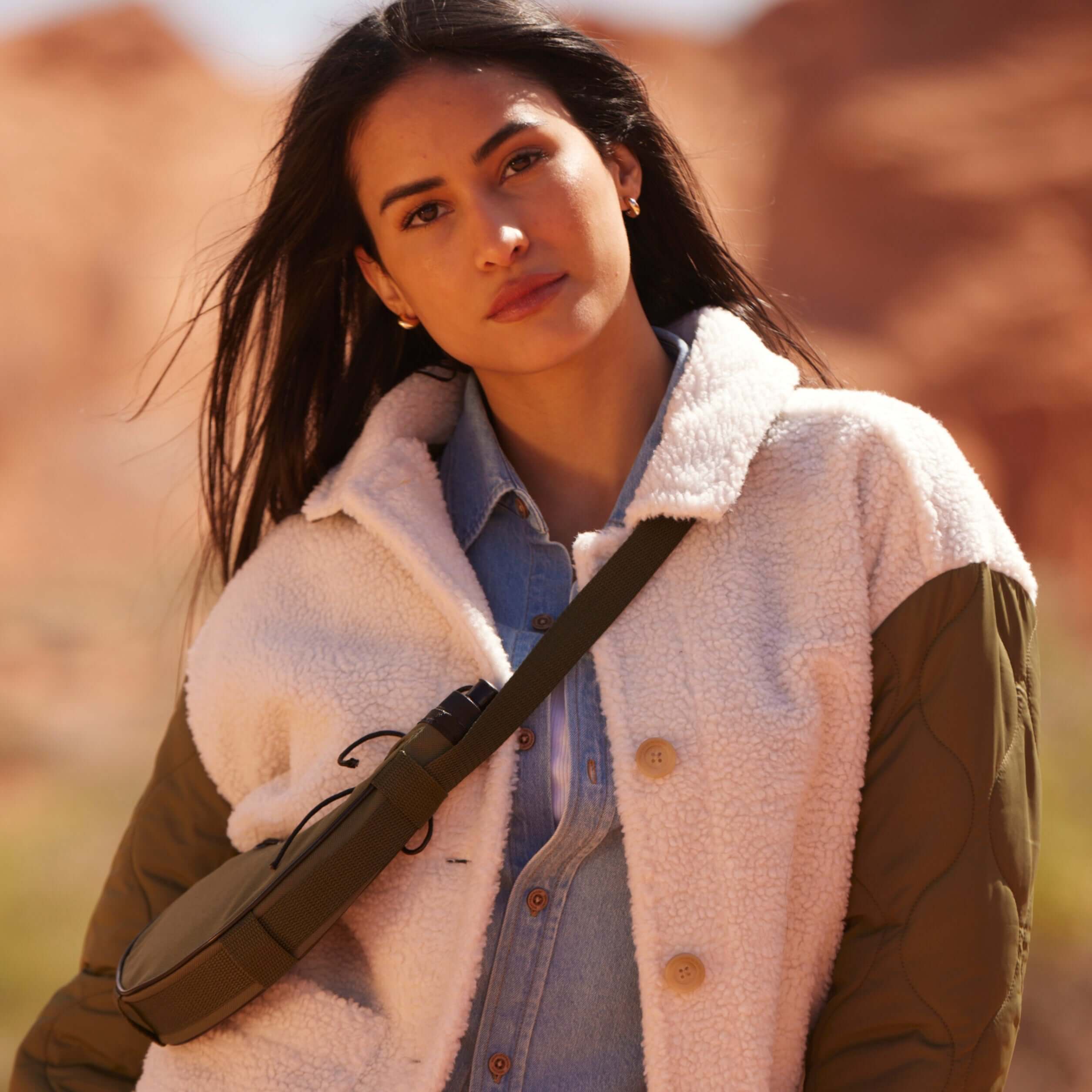 Woman in a cozy green mixed media quilted jacket posing outdoors with a stylish bag, showcasing a warm, classic fit.
