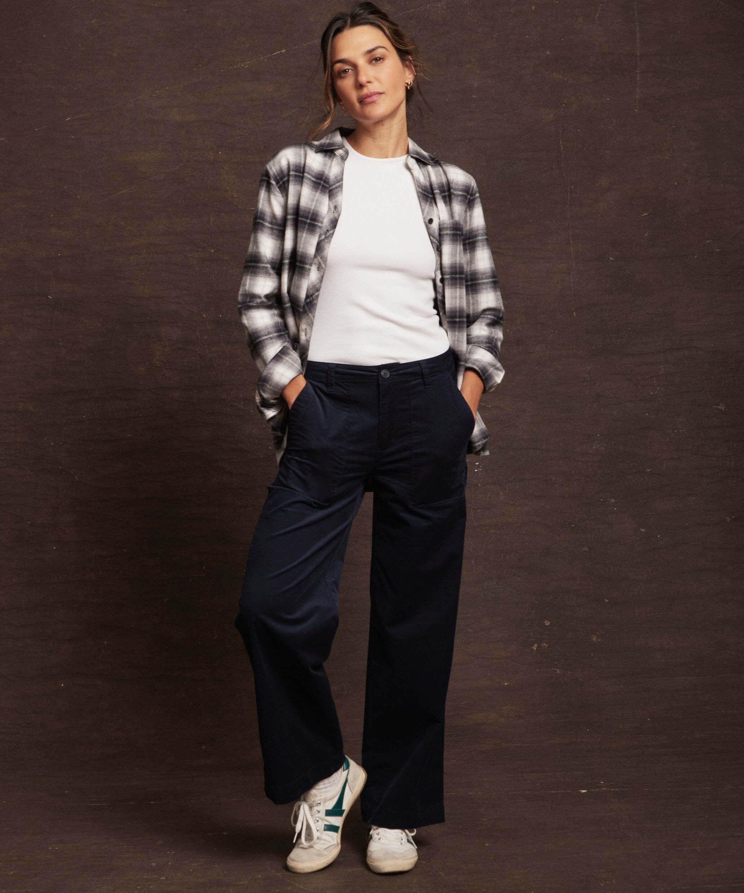 Model wearing women's wide leg corduroy pant in navy, styled with a plaid shirt and sneakers, showcasing a relaxed yet chic look.